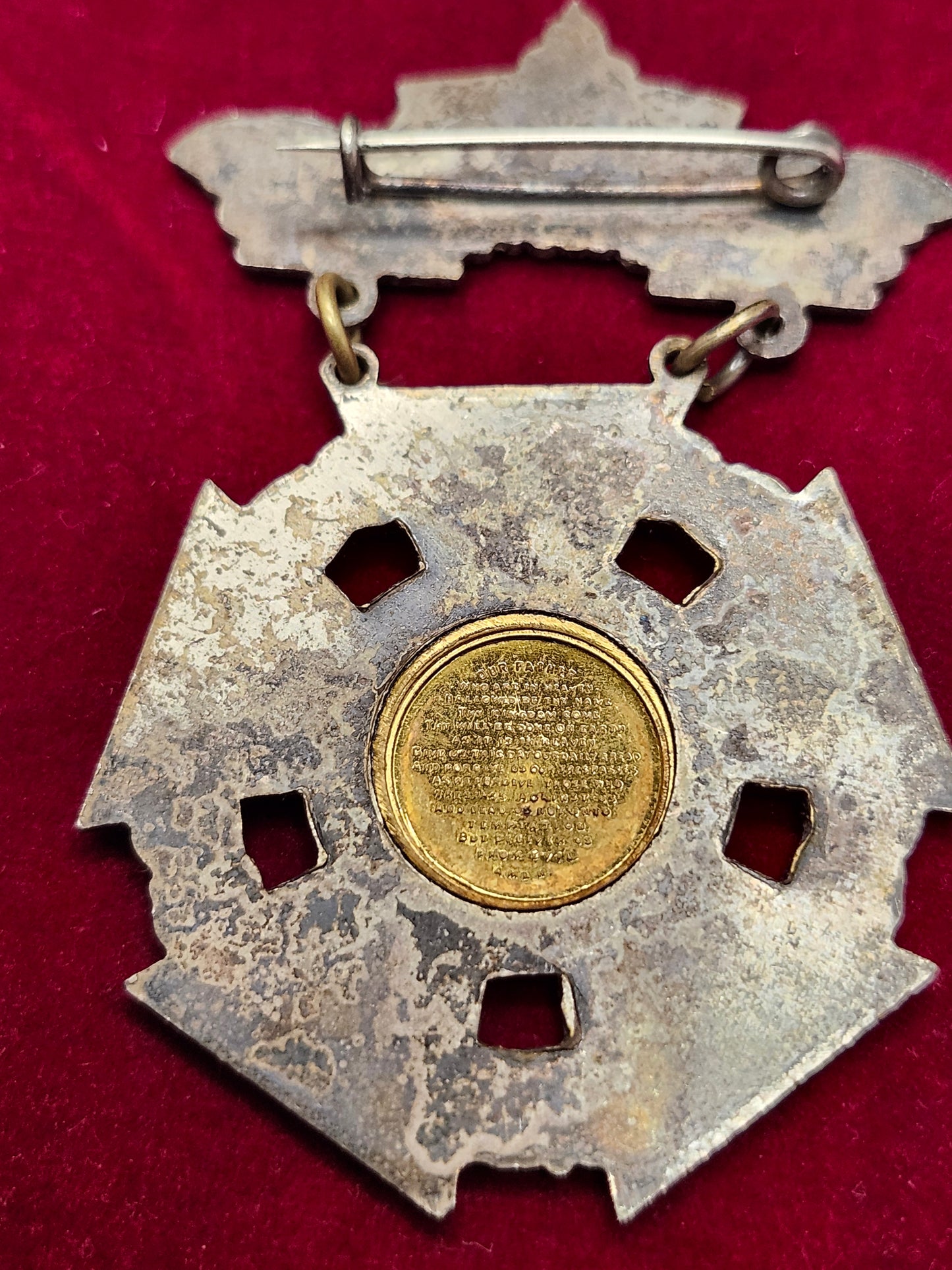 Decorative metal object with a central gold coin on a red background