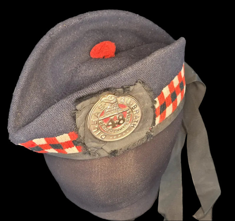 Gray cap with a red badge and checkered band on a dark background