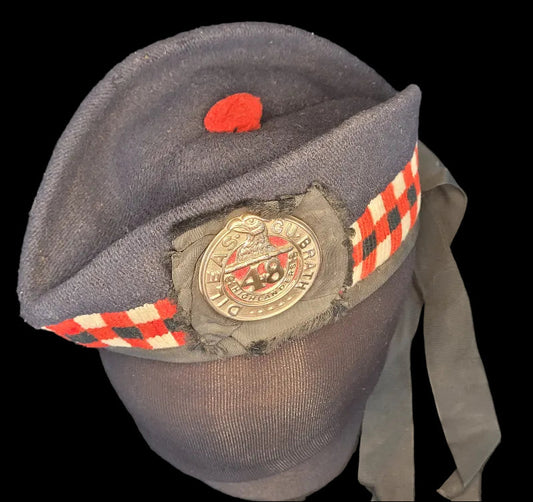 Gray cap with a red badge and checkered band on a dark background